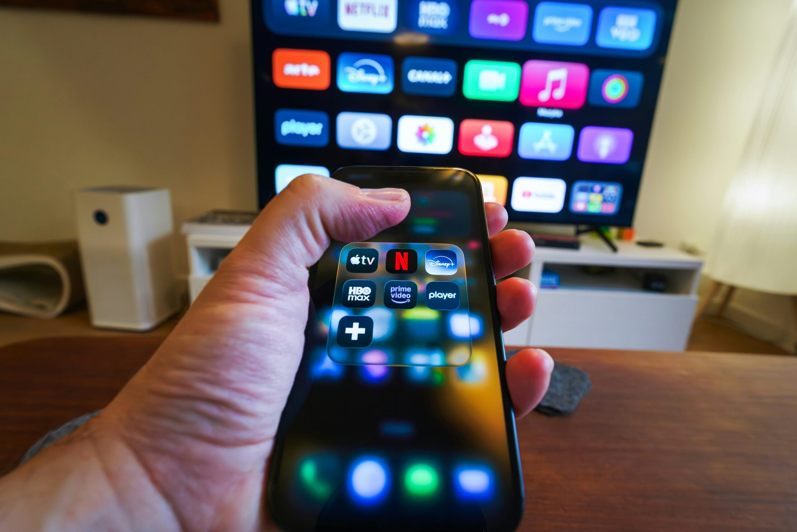 Telefon streamingalkalmazásokkal, a háttérben televízióval