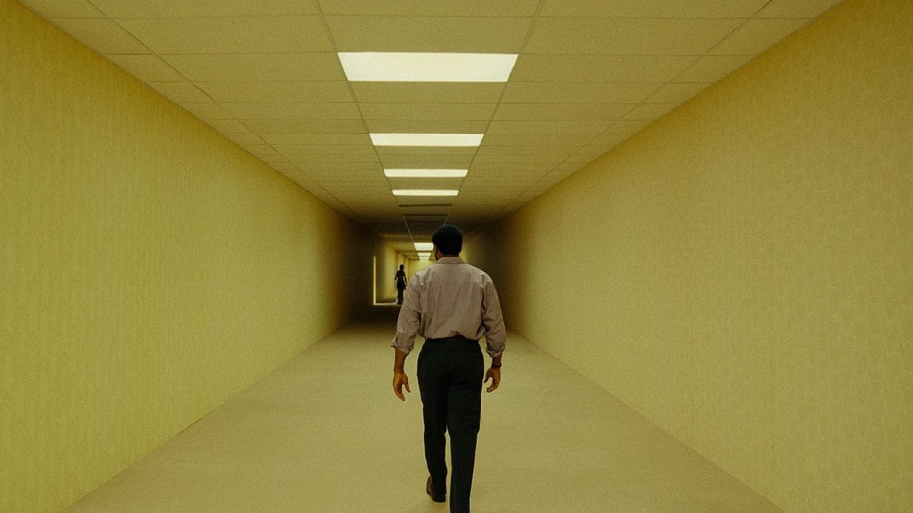 A Backrooms film sárga folyosójában két alak látható