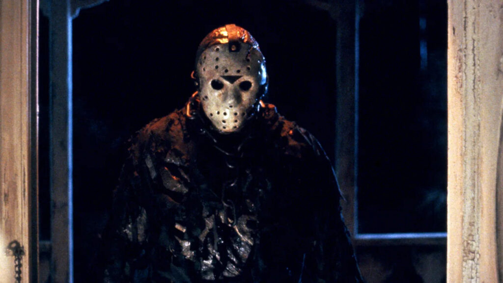Jason Voorhees nem is az első Péntek 13. gyilkosa volt – így született meg a hokimaszkos horrorlegenda Jason Voorhees hokimaszkban egy sötét faház bejáratánál a Péntek 13. egyik jelenetében