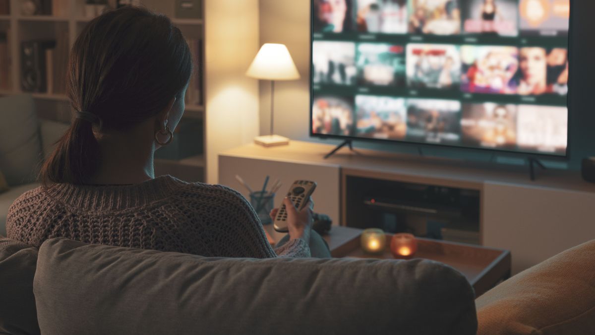 Egy nő egyedül választ műsort a televízióján